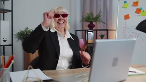 happy senior business woman dancing victory dance celebrating weekend holiday success win in office