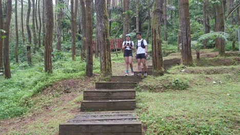 indonesian couple on forest trail run with woman recording video on smartphone