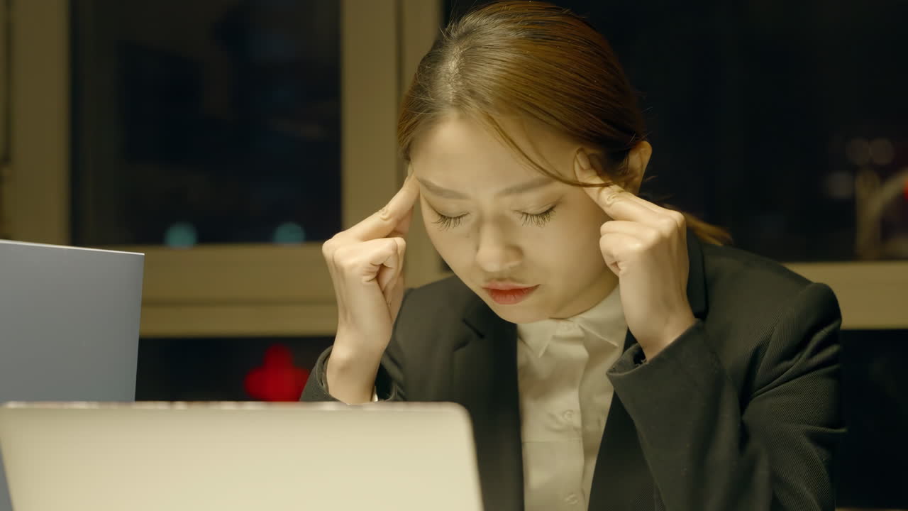 피곤한 여성 사무실 직원: 밤 늦게 오버타임을 하는 동안 두통과 불편을 겪는 젊은 여성의 초상화 낮은 에너지 늦은 시간에 수면이 필요합니다.