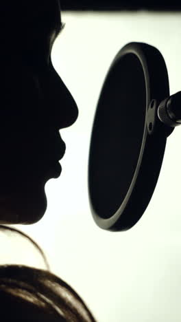 woman singing in the recording studio. profile of a woman with a beautiful face and lips. black and white vertical video