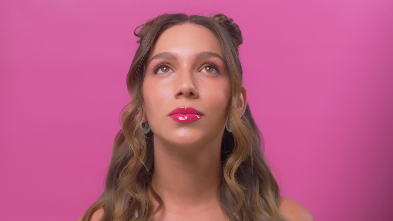 Woman posing in slow motion with glossy makeup while lifting her gaze toward the camera
