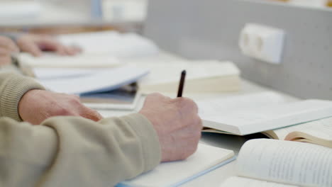 unrecognizable senior man writing outline in notebook