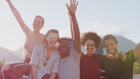 portrait of friends standing in front of open top hire car on summer vacation