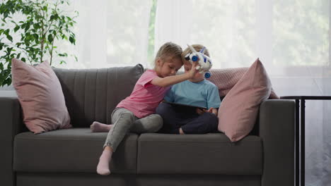 girl plays with airplane when boy watching cartoon on tablet