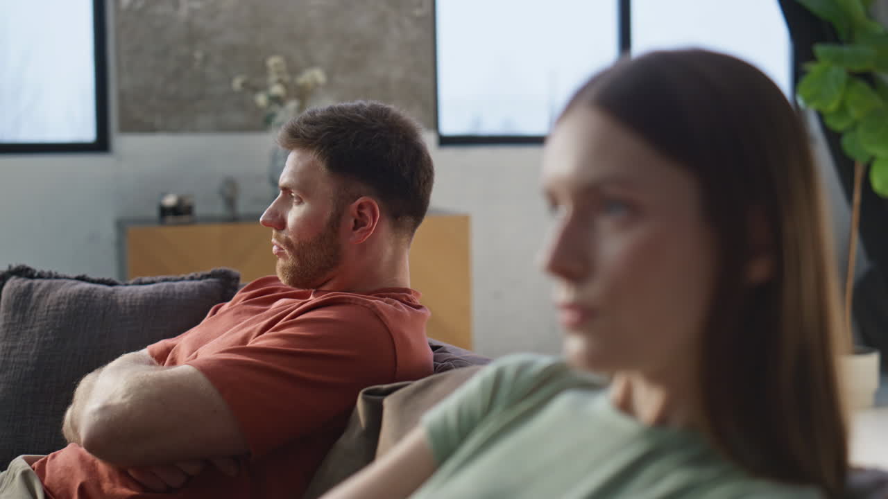 Upset wife offended husband showing dissatisfaction at home sofa closeup
