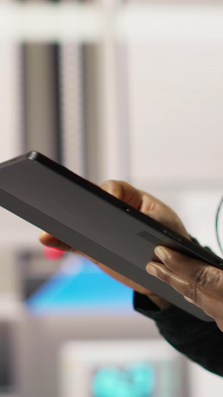 Vertical video Engineer in smart factory oversees robotic assembly lines using tablet app