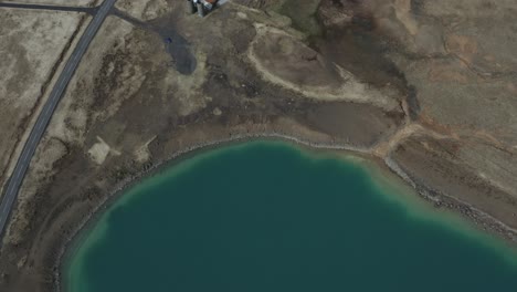 Green-turquoise-lake-Iceland-drone-Birdseye-aerial-reveal-road-and-building