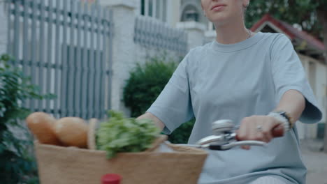 woman riding a bike with a basket of groceries