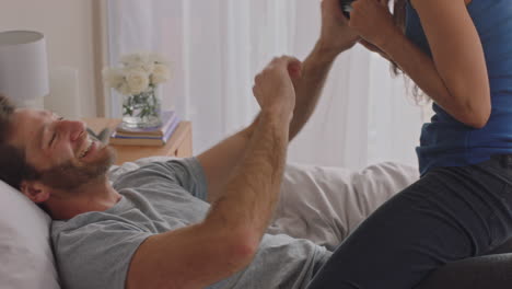 행복한 커플이 카메라를 사용하여 함께 사진을 찍고 침대에서 집에서 재미있게 로맨틱한 관계를 즐기며 서로 사진을 찍고 있습니다.