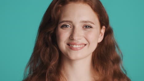 Redheaded-girl-in-front-of-camera-on-turquoise-background.