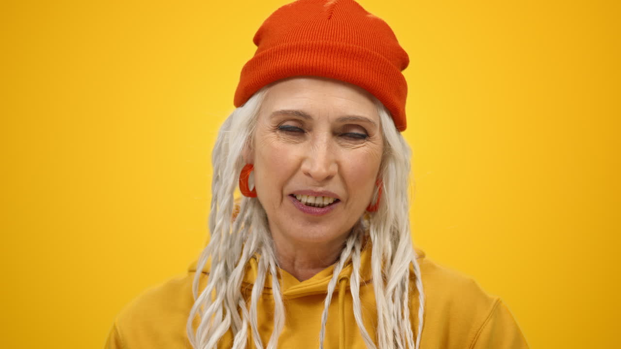 기하는 은 여자가 내부에서 카메라를 포즈. 미소 짓는 여자가 실내에서 록 제스처를 보여줍니다.