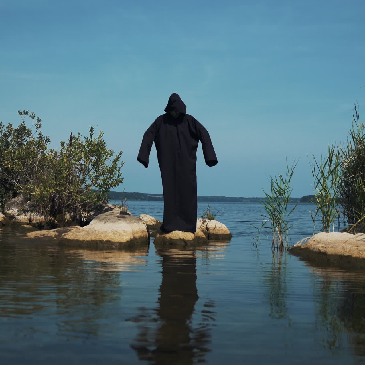 Terrible demon standing in the river. Scary figure in black mantle.