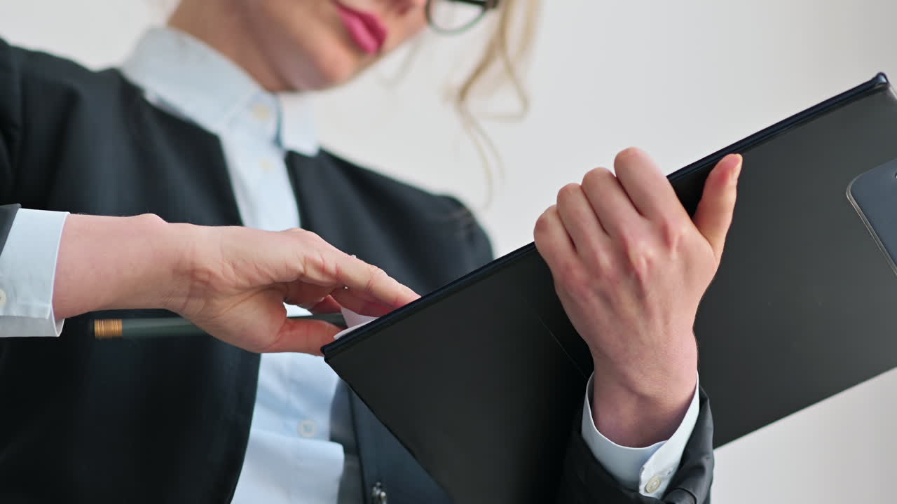 Close up of woman's hands going through the pages on a clipboard, holding a pencil