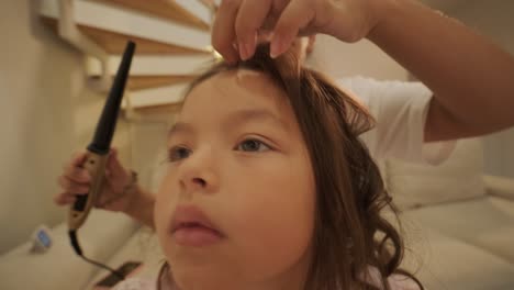 pregnant mother styling her daughter's hair at home