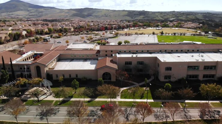 Panorâmica aérea de uma escola suburbana com a bandeira americana hasteada.