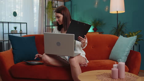 Young-businesswoman-working-with-laptop-computer-and-documents,-planning-expenses-budget-at-home