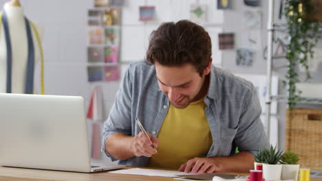 Männlicher-Student-Oder-Geschäftsinhaber,-Der-Mit-Einem-Laptop-Im-Studio-In-Der-Modebranche-Arbeitet