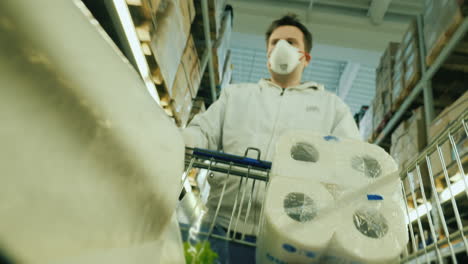 a man carries toilet paper and groceries in a trolley because of the surge in demand for goods during the epidemic