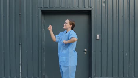 female nurse wearing medical blue uniform dancing happily outside