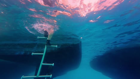 Diver's-feet-going-up-underwater-staircase-stairs-revealing-person-going-out-sea