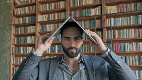 un tipo gracioso en la biblioteca con una computadora portátil sobre la cabeza.