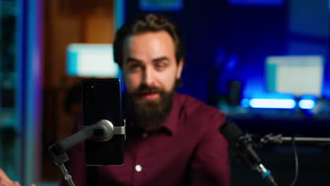 focus on cellphone used by media star using on selfie stick to film vlog