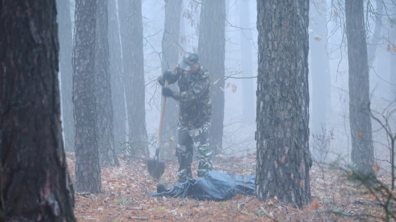 범죄자가 숲에서 피해자의 시체를 파다