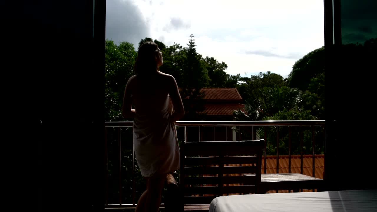 una mujer con una toalla está en el balcón del hotel