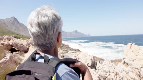 Senior-biracial-woman-in-mountains-resting-at-sea,-in-slow-motion