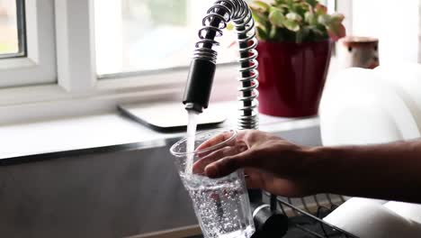 person filling glass by tap water