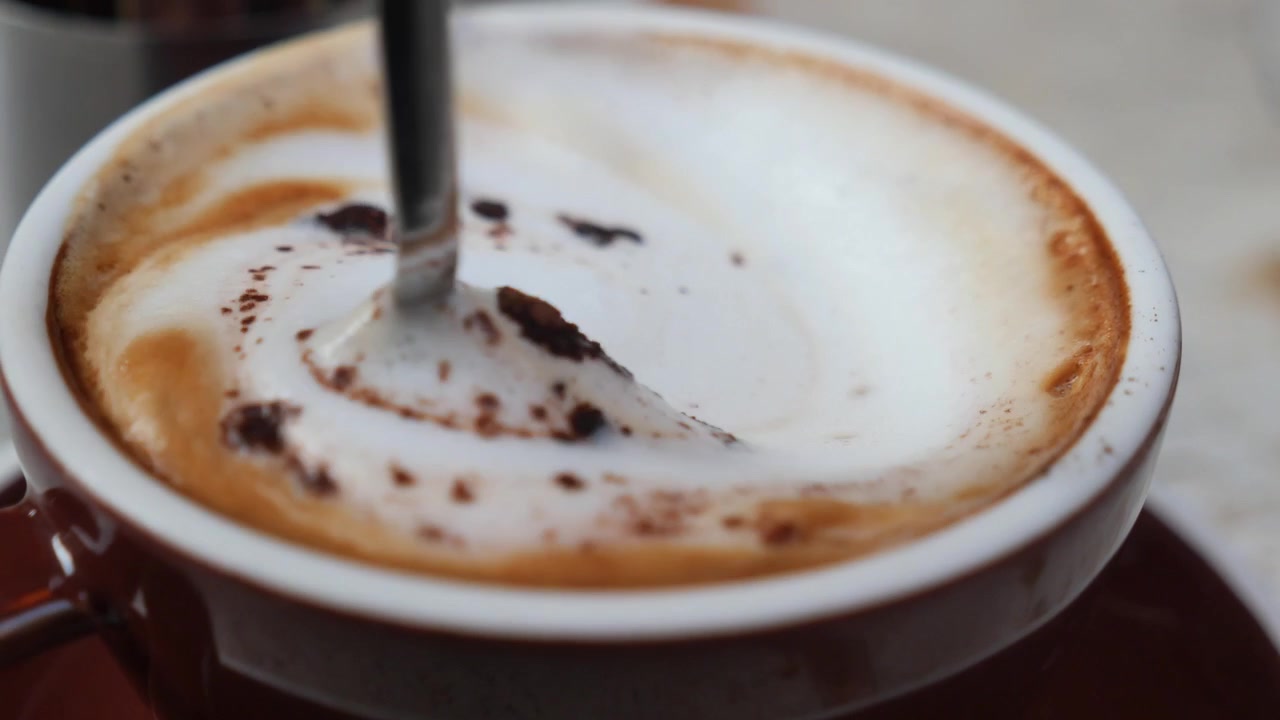 Primo piano di un cucchiaino che mescola una tazza di cappuccino