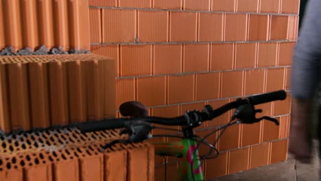 man with a bike next to a brick wall