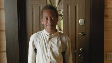 portrait of an boy waving at camera at home and then opening the door and leaving