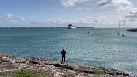 Dunmore-East-Waterford-Mann-Tief-In-Gedanken-Versunken-Und-Blickt-Auf-Ein-Kreuzfahrtschiff,-Das-An-Einem-Sommertag-Im-Hafen-Festgemacht-Hat