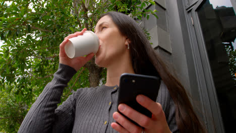 Vista-De-ángulo-Bajo-De-Una-Mujer-Feliz-Usando-Un-Teléfono-Móvil-En-La-Ciudad-4k