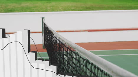 tennis net stretching diagonally across court, showing black mesh white cord and metal posts