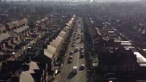 aerial rising view establishing rows of victorian terraced neighbourhood homes with a long road leading towards town centre at sunrise