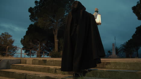 woman climbs stairs with cloak in square for religious rite a night with lantern