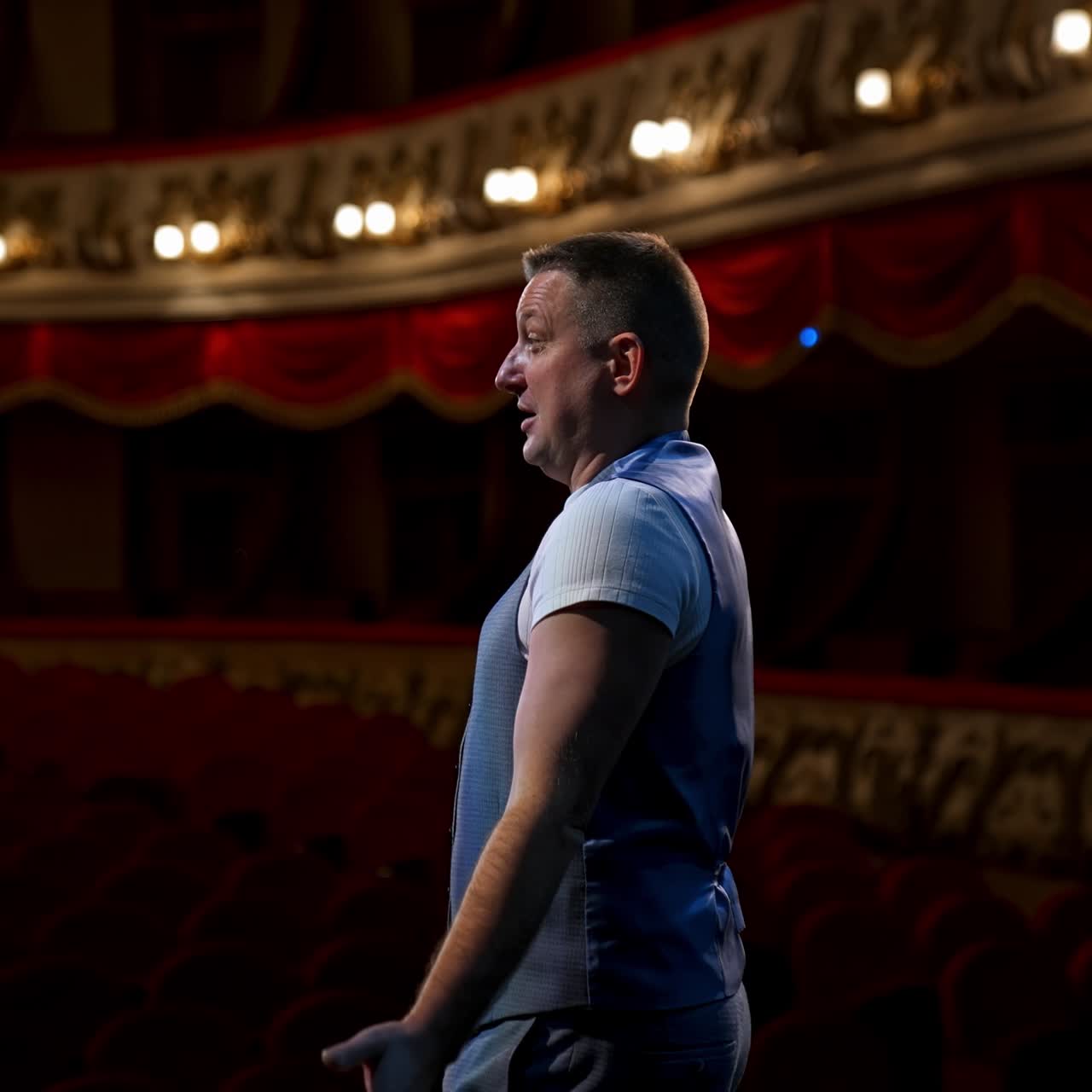 Man takes of protective mask from face and ready to perform from the stage. Rich interior of classic theater. End of lockdown