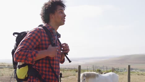 Happy-african-american-couple-with-backpacks,-hiking-with-trekking-poles-together,-slow-motion