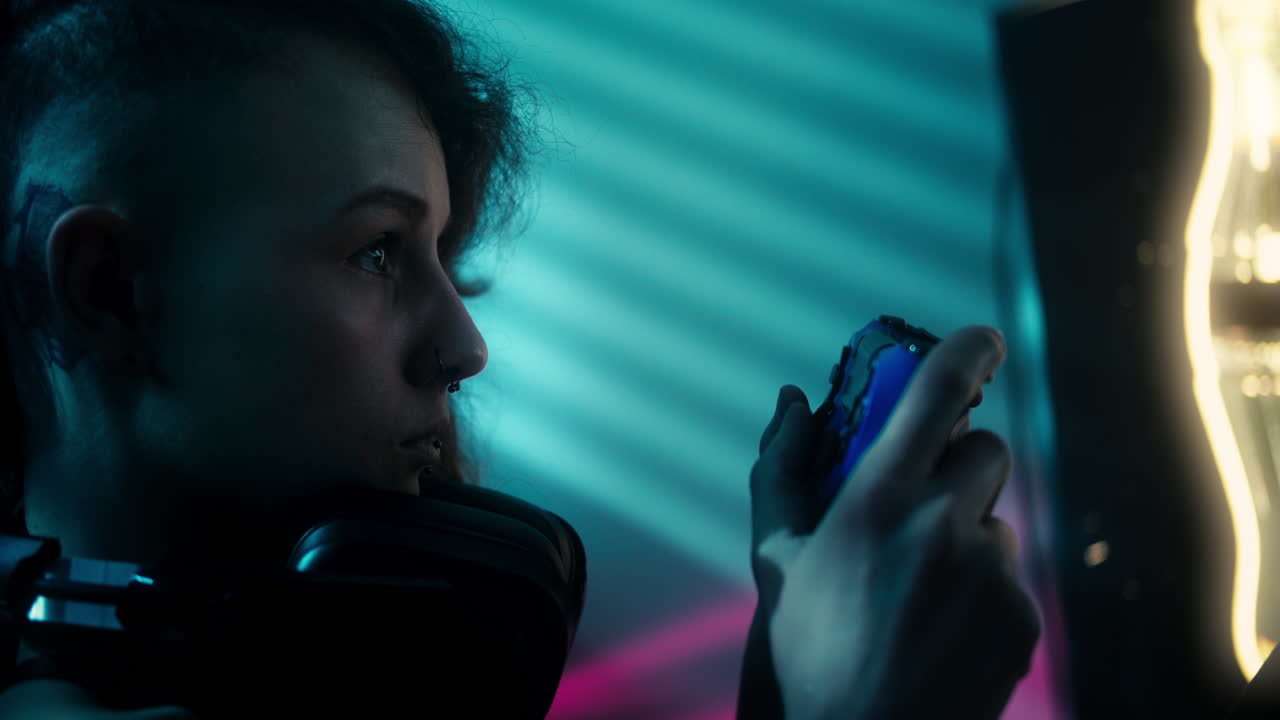 Close up of a girl playing video games in a neon-lit room on her controller while wearing headphones and focusing on the match