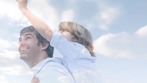 animation of clouds over happy caucasian father and son having fun outdoors