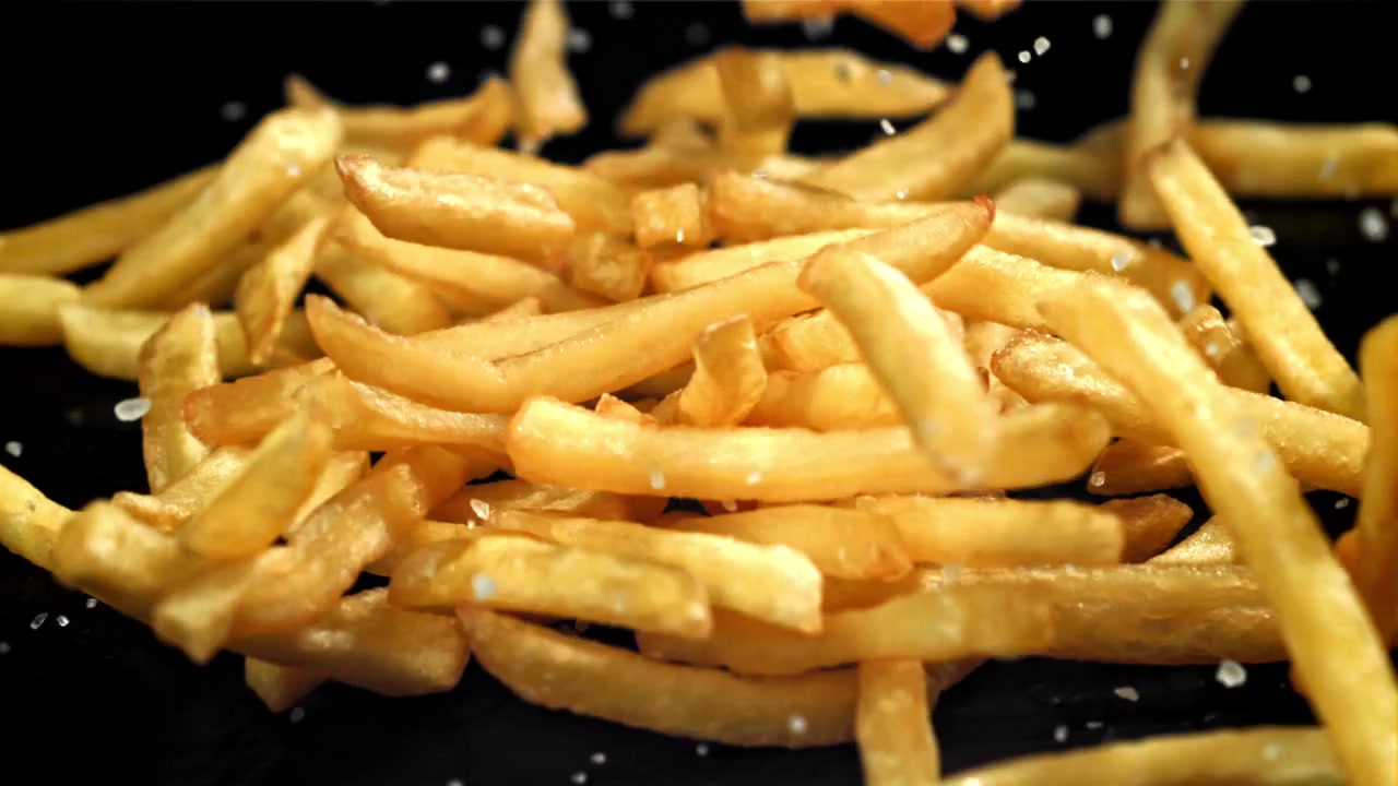 Crispy Golden French Fries and Salt Falling in Slow Motion