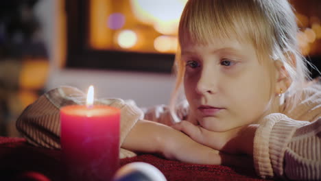 portrait of a child looks at a candle makes a wish on christmas eve