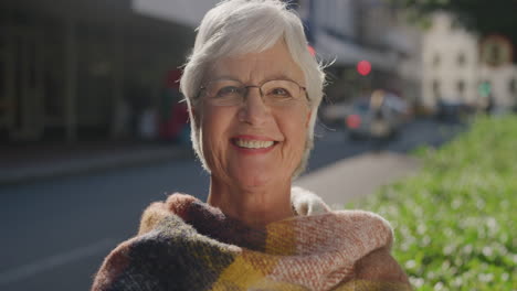 Porträt-Einer-Glücklichen-Alten-Frau,-Die-Fröhlich-Lächelt-Und-Einen-Erfolgreichen-Ruhestandslebensstil-An-Einem-Sonnigen-Tag-In-Der-Stadt-In-Der-Stadtstraße-Genießt.-Sie-Trägt-Einen-Schal-Und-Trägt-Einen-Schal.-Selbstbewusste-Kaukasische-Frau-Im-Ruhestand-In-Zeitlupe