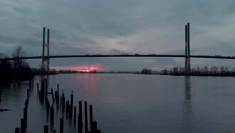 Drohnen-4K-Aufnahmen-Der-Alex-Fraser-Brücke,-Aufnahme-Einer-Modernen-Hängebrücke-Und-Des-Sonnenuntergangs-Aus-Der-Tiefwinkelansicht,-Während-Autos-Und-Lastwagen-Die-Brücke-überqueren