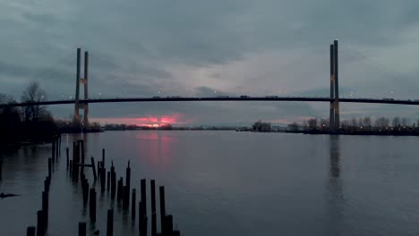 drone 4k-beeldmateriaal alex fraser bridge lage hoek opname van hangende moderne brug en zonsondergang terwijl auto&#39;s en vrachtwagens de brug oversteken