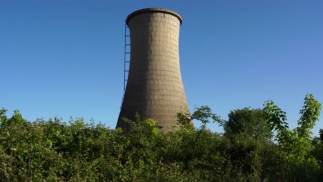 Hoher-Betonturm-Der-Kohlekraftwerksstation,-Bedeckt-Mit-Grünem-Gras-Und-Dornen-Auf-Verlassenem-Industriegebiet