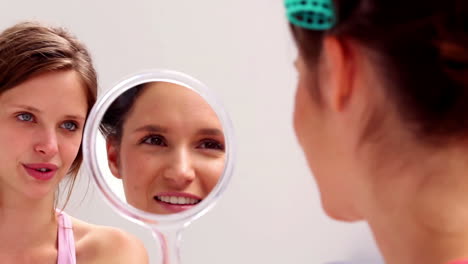 Girl-wearing-rollers-looking-in-mirror-and-talking-to-friend