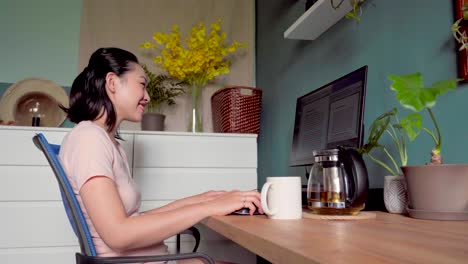 asian woman reading document on computer and working at home